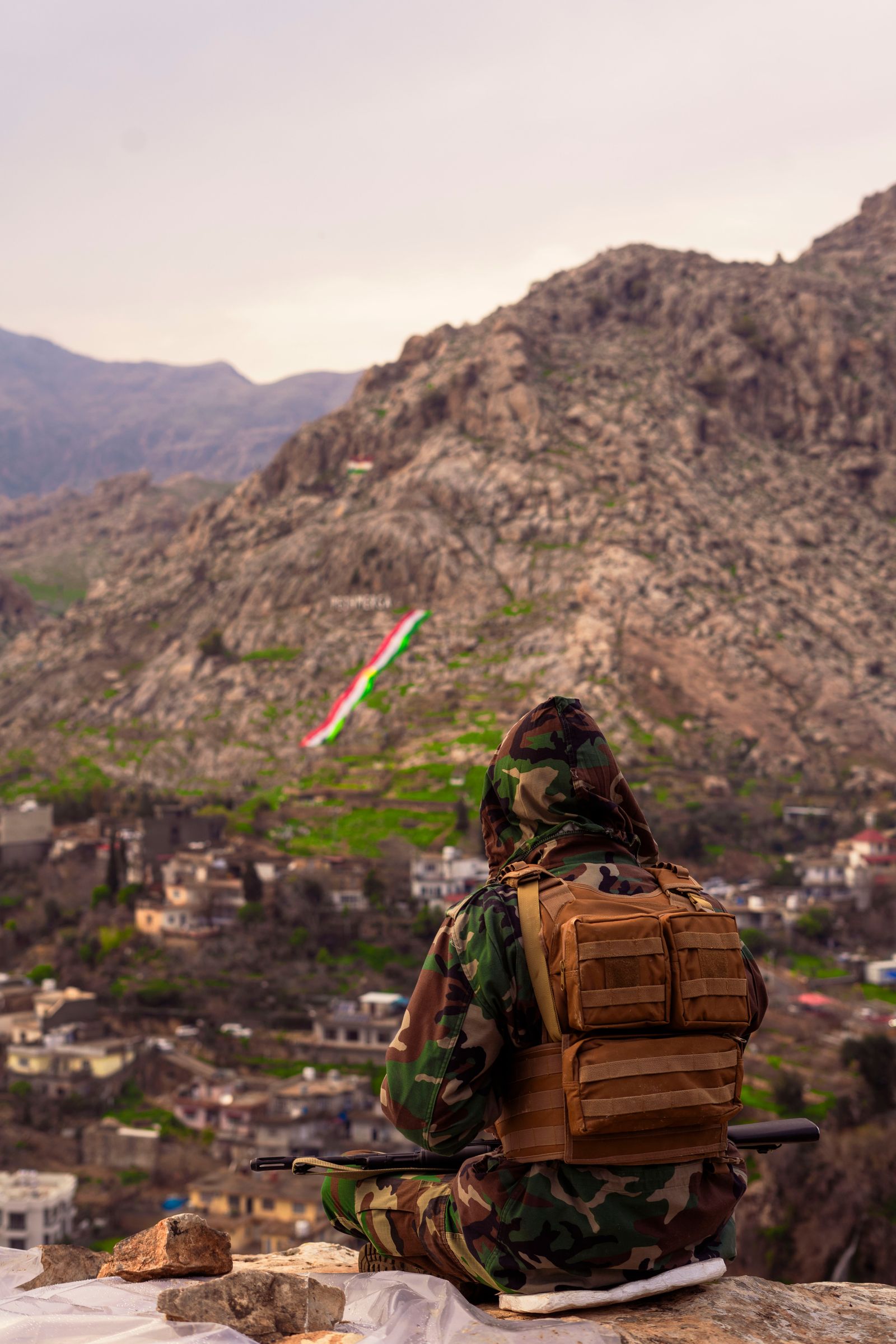 Soldier in camouflage surveying rugged mountain terrain